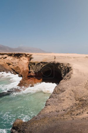 Téléchargez les photos : Femme explorant les falaises de la côte sauvage et désertique de l'île canarienne de Fuerteventura lors de son voyage d'aventure d'été - en image libre de droit