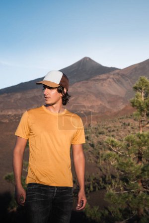Téléchargez les photos : Jeune homme dans un paysage de montagne au coucher du soleil à tenerife avec le pic Teide en arrière-plan. - en image libre de droit