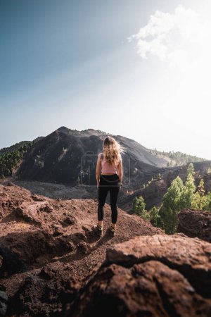 Photo for Woman with long hair marveling at the volcanic landscape of the Cumbre Vieja lava mountains at sunset, during her adventure on the Canary Island of La Palma - Royalty Free Image