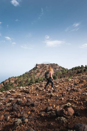 Photo for Girl ascending a volcanic rock mountain of cumbre vieja on a sunny day on the canary island of La palma - Royalty Free Image