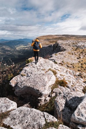 Téléchargez les photos : Homme en vêtements chauds marchant sur une crête rocheuse dans la chaîne de montagnes Gorobel par une journée ensoleillée d'automne - en image libre de droit