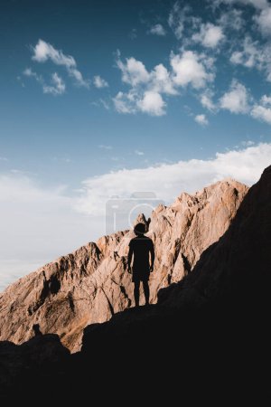 Téléchargez les photos : Jeune homme rétroéclairé avec des montagnes de rochers ensoleillés dans les Picos de Europa entre Asturies et Cantabrie - en image libre de droit