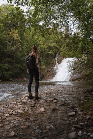 Foto de Mujer de pie disfrutando de la cascada de la Poza de los Caballos del río Nervión en Delika, Álava, País Vasco. - Imagen libre de derechos
