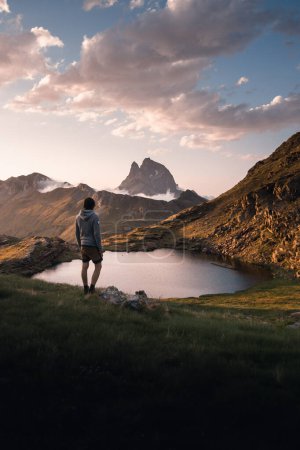 Téléchargez les photos : Jeune homme aventureux profitant de la vue sur les lacs Anayet et le pic Midi d'Ossau au coucher du soleil. dans les pyrénées - en image libre de droit