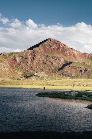 Téléchargez les photos : Montagnes colorées illuminées par le soleil couchant et reflétées dans le lac. Avec une personne au milieu. Dans les lacs d'Anayet, dans les Pyrénées. - en image libre de droit