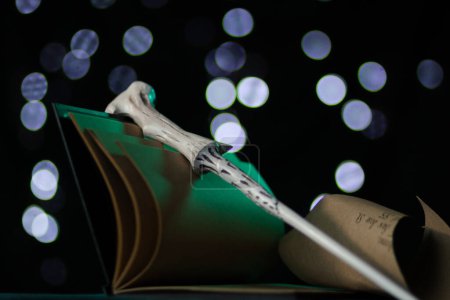 Foto de El diario de Tom Riddles con una varita mágica en él en luz verde de neón yace bajo brillantes luces frías en la oscuridad. Artefactos mágicos, recuerdos de cerca - Imagen libre de derechos