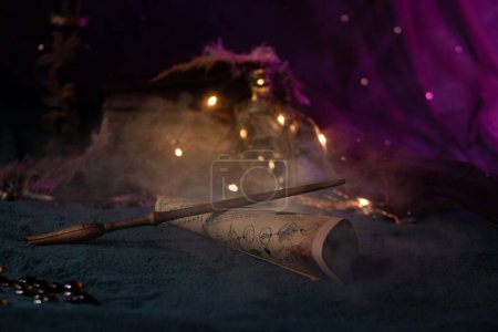 Foto de La varita Luna lavguds descansa sobre un pergamino de hechizos entre artefactos mágicos iluminados por luces de hadas, luciérnagas y humo sobre un fondo rosa. Esquina de las brujas jóvenes, primer plano - Imagen libre de derechos