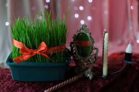 Photo for Greeting card for Nevruz holiday, Iranian new year. Traditional symbols of wheat germ, mirror, candle on red background with shining lights, close-up - Royalty Free Image