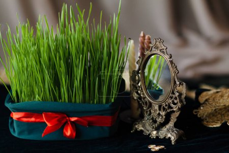 Foto de El germen de trigo está atado con una cinta roja entre velas, un símbolo de la fiesta de Novruz del nuevo año del pueblo iraní. Celebración del equinoccio de primavera, primer plano - Imagen libre de derechos