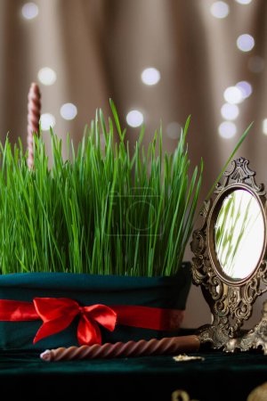 Téléchargez les photos : Le germe de blé est attaché avec un ruban rouge parmi les bougies, un symbole de la fête de Novruz de la nouvelle année des peuples iraniens. Fête de l'équinoxe de printemps, plan rapproché verticalement - en image libre de droit