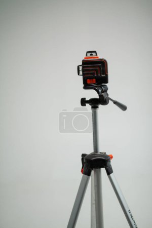 Photo for Laser level on white background projecting perpendicular lines mounted on a tripod. An instrument for accurate height measurement and installation, used in construction, renovation, design. Vertically - Royalty Free Image