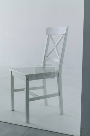 Foto de Una silla blanca con respaldo se apoya sobre un fondo liso de un ciclorama ligero. Decoración minimalista de estudio fotográfico, marco vertical, objeto aislado - Imagen libre de derechos