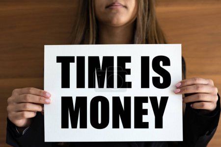 Foto de El tiempo es dinero. La mujer sostiene una página blanca con texto "El tiempo es dinero" en letras negras. Ganar dinero, urgencia, negocios, comercio y beneficios. - Imagen libre de derechos