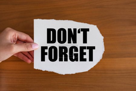Photo for Don't forget - close up text on the slip. Woman hand holds a piece of paper with text. Information sign, opening event, business and premiere event. - Royalty Free Image