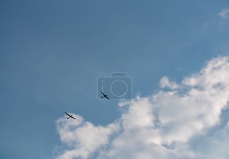 Photo for Glider near clouds. Small plane pulls glider to the sky to start the gliding flight. Thy sky is blue with some clouds. - Royalty Free Image