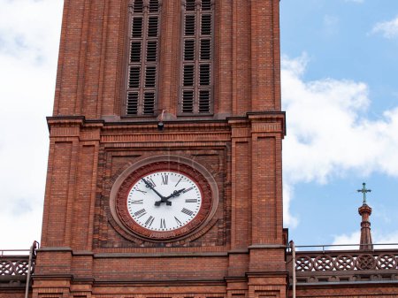 Photo for Church clock with white clock face. Close up red brick church tower with clock. Ancient clock with old white and black clock-face. Sunny day with blue sky and few clouds. - Royalty Free Image