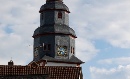 Photo for Close up church tower with clock. Ancient clock with blue and golden shiny clock-face. Sunny day with blue sky and few clouds. - Royalty Free Image