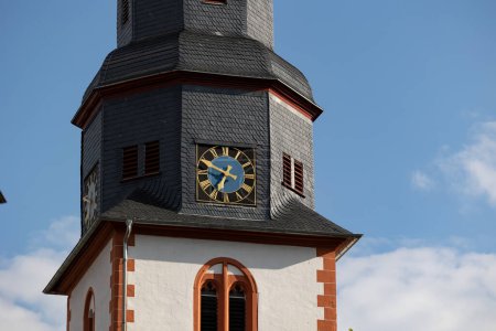 Photo for Close up church tower with clock. Ancient clock with blue and golden shiny clock-face. Sunny day with blue sky and few clouds. - Royalty Free Image