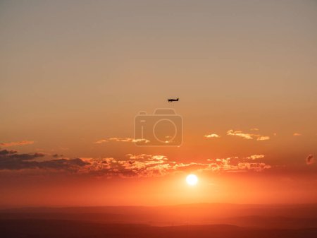 Téléchargez les photos : Un avion vole à l'horizon pendant le coucher du soleil. Au sommet du Feldberg en Hesse, Allemagne. - en image libre de droit