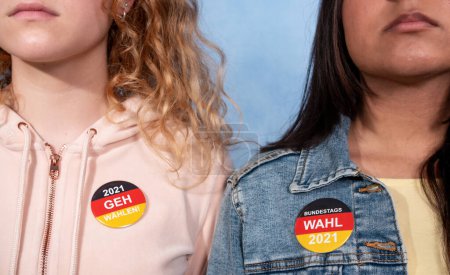 Photo for Two young women with German election buttons on their clothes. Statement: "2021 Geh Whlen" (2021 Go Vote) and "Bundestagswahl 2021" (Federal Election 2021). - Royalty Free Image