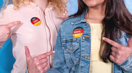 Photo for Two young women with fingers pointing to the election buttons on their clothes. Statement: "2021 Geh Waehlen" (2021 Go Vote) and Bundestagswahl 2021 (Federal Election 2021). - Royalty Free Image