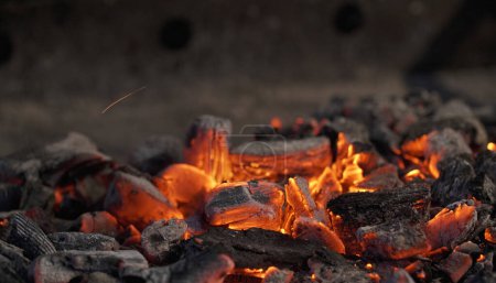 Téléchargez les photos : Du charbon de bois sur un gril. Gros plan sur le charbon de bois et les braises chaudes. Chaleur, température, temps de barbecue. - en image libre de droit