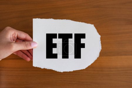 Téléchargez les photos : ETF, (Exchange Traded Funds) main de femme tient un morceau de papier avec une note. Entreprise, investissement, négoce, profit. - en image libre de droit