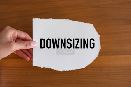 Downsizing. Woman hand holds a piece of paper with a note, downsizing. Small, reduction, zoom out, scale, change.