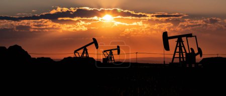 Landscape with silhouette of oil pumps. Landscape like Texas with glowing sky during sunset and some clouds. Oil and gas industry, drilling and oil production. concept. 3D illustration