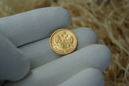 Photo for A gold coin of the Russian Empire in a numismatist's hand. Numismatics and Investments. - Royalty Free Image
