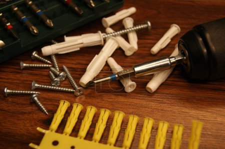Dowels, screws, screwdriver, bit set. A mess in the assembly work process on the table. 