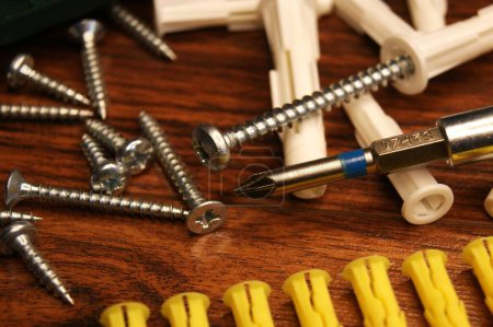 Photo for A mess in the assembly work process on the table. Dowels, screws, screwdriver, bit set. - Royalty Free Image