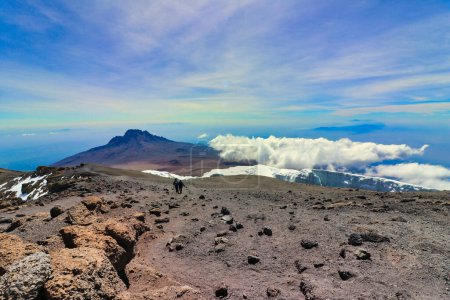 Photo for Hikers descend towards Stella Point after summiting on Kilimanjaro with Mawenzie Peak in background, Tanzania - Royalty Free Image