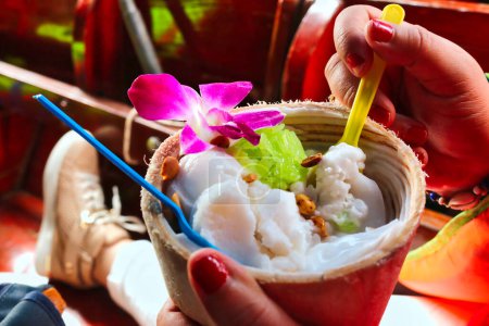 Photo for Coconut Ice cream enjoyed by a visitor to the Damnoen Saduak Floating Market, Ratchaburi near Bangkok, Thailand - Royalty Free Image