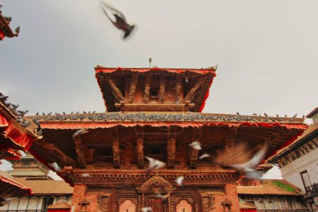 Pigeons take flight at the busy Durbar square, landmark city center with historic wood built mandaps,pavillions,temples and shrines at Kathmandu,Nepal