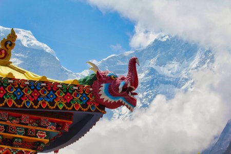 Mythical Dragon carvings on the roof of the Tengboche Monastery with snow clad mountains in Nepal