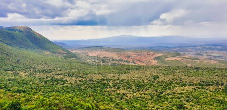 Herrlicher Panoramablick auf das Great African Rift Valley mit dem Mount Suswa im Hintergrund und Regenwolken vom Rand der Böschung bei Nairobi, Kenia, Afrika