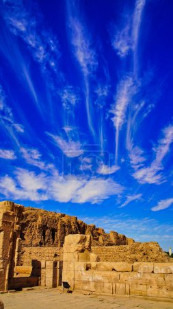 Schöne Wolkenmuster und strahlend blauer Himmel mit Lehmziegelmauern und Überresten des Horustempels in Edfu, der während der ptolemäischen Ära zwischen 237 und 57 v. Chr. in der Nähe von Assuan, Ägypten, erbaut wurde.