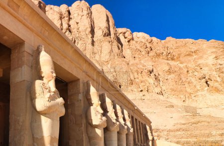 Statues massives de la Grande Femme Pharoah Hatchepsout avec le escroc et le fléau comme souverain de l'Egypte sculpté dans le grès dominent les colonnes extérieures du temple mortuaire près de Louxor, Egypte