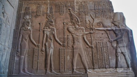 Wandrelief von Kleopatra III., Kleopatra II. und Ptolemäus VIII. Euergetes vor Horus im Bokeh-Fokus im Tempel von Sobek und Haroeris von Ptolemäus-Pharaonen in Kom Ombo, bei Assuan, Ägypten