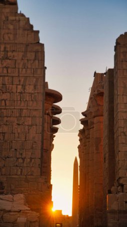 Morning sunlight fills the central passage of the Great Temple of Karnak with soft focus views of the Thutmose I Obelisk at the Karnak temple complex dedicated to Amun-Re in Luxor,Egypt