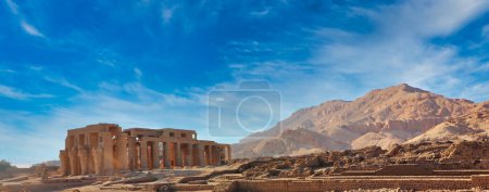 Wide angle view of the Ramesseum, the Mortuary Temple of Pharoah Ramesses II the Great with the backdrop of the Theban Hills on a bright afternoon with blue skies at Luxor, Egypt 