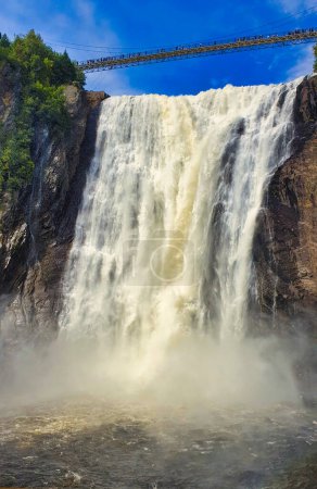 Thundering waters of the Montmorency Waterfalls, 83 m high on the Montmorency river on a bright sunny day with blue skies near Quebec city, the capital of Quebec province,Canada