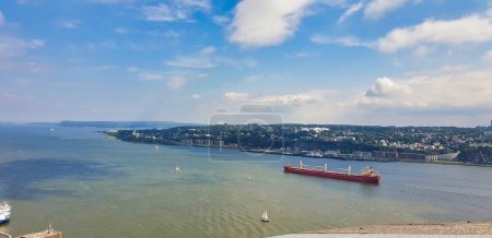 Merchant ships ply on the St. Lawrence river with the town of Levis in the background in this wide angle view from the top of the Citadel  in Quebec city, the capital of Quebec province,Canada