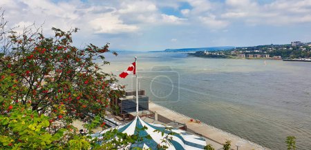 Panoramic view from the Dufferin terrace of the St. Lawrence river with the ports of Quebec and Levis on either shores, Canada Flag visible in foreground in Quebec city, Canada