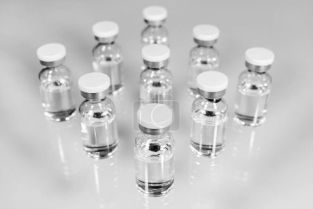 Téléchargez les photos : Flacons en verre avec vaccin transparent injectable sur surface blanche. Médicaments et soins de santé - en image libre de droit