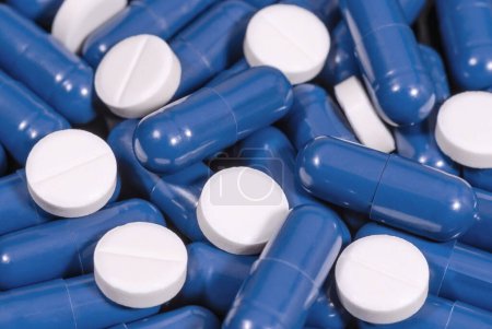 Téléchargez les photos : Capsules bleues et pilules blanches en gros plan. Médicaments et santé. Concept pharmaceutique - en image libre de droit