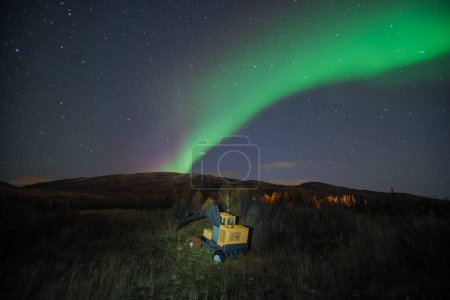 Photo for Abandoned heavy machinery excavator in the landscape at night under northern lights aurora, industrial waste in the arctic regions - Royalty Free Image