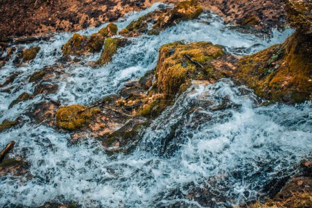 Foto de Una cascada de dolomita de piedra con una fuerte corriente de agua que fluye hacia abajo. Hay un bosque cerca.. - Imagen libre de derechos