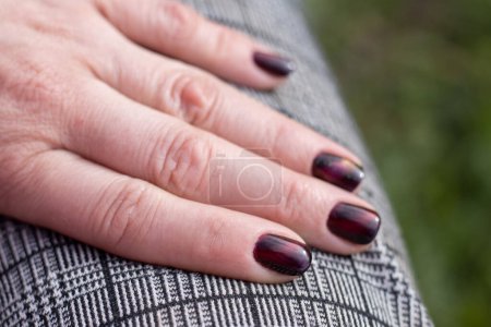 Foto de Una mano con hermosas uñas cuidadas colocadas en una pierna. Paisaje. - Imagen libre de derechos